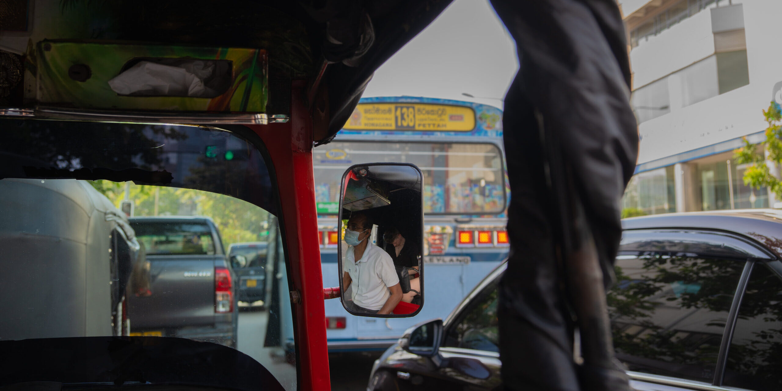 The busy streets of Colombo, Sri Lanka from inside a tuk-tuk with cars and buses on the road