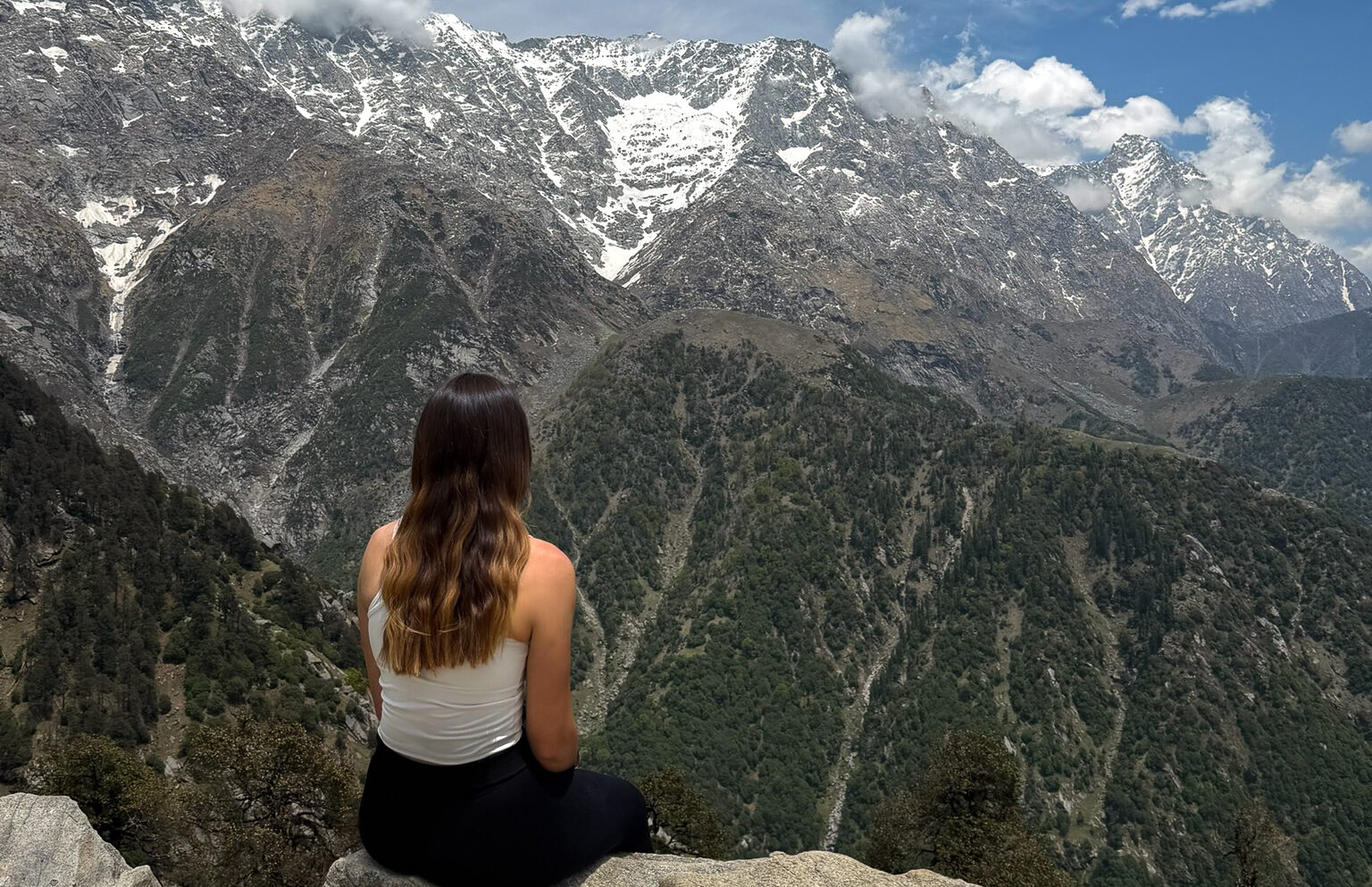 Sitting at the top of a mountain edge looking at the insane views after the Triund Trek