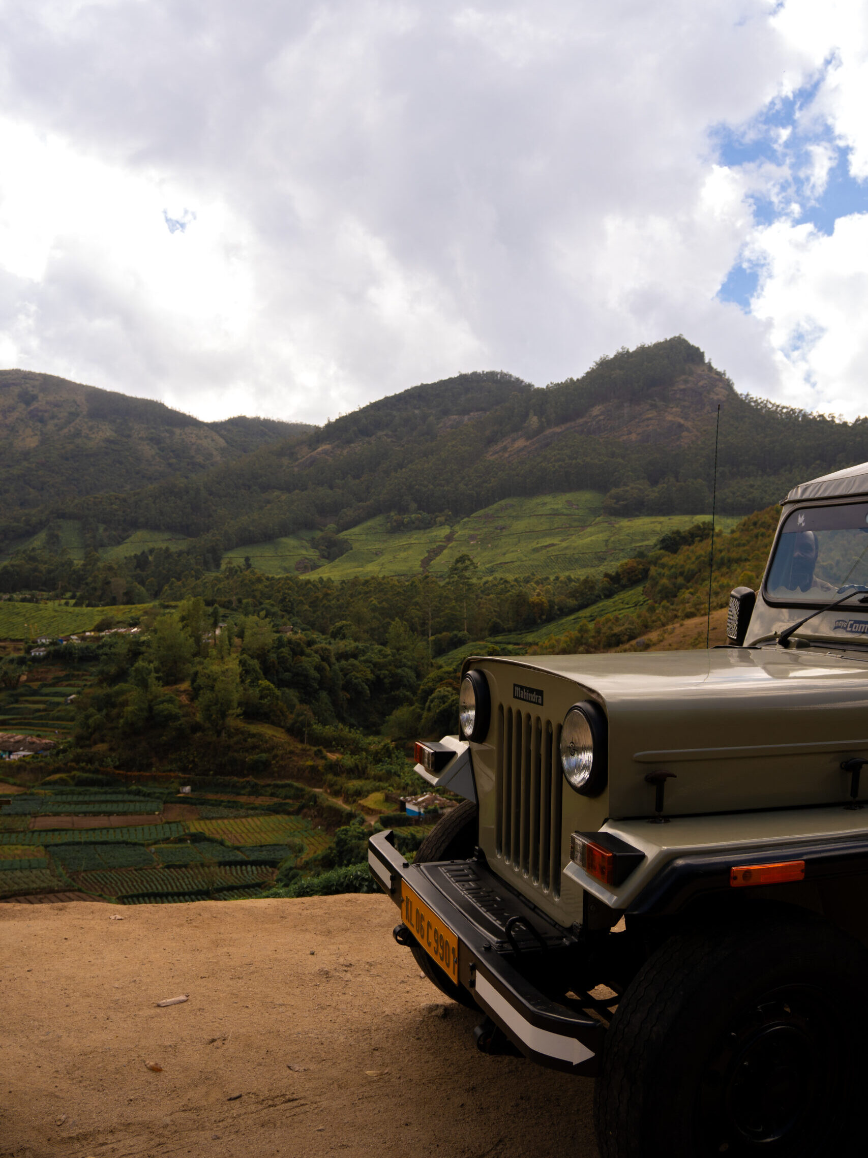 The Jeep parked up during the tour at a view of lush green tea plantations with houses and allotments below