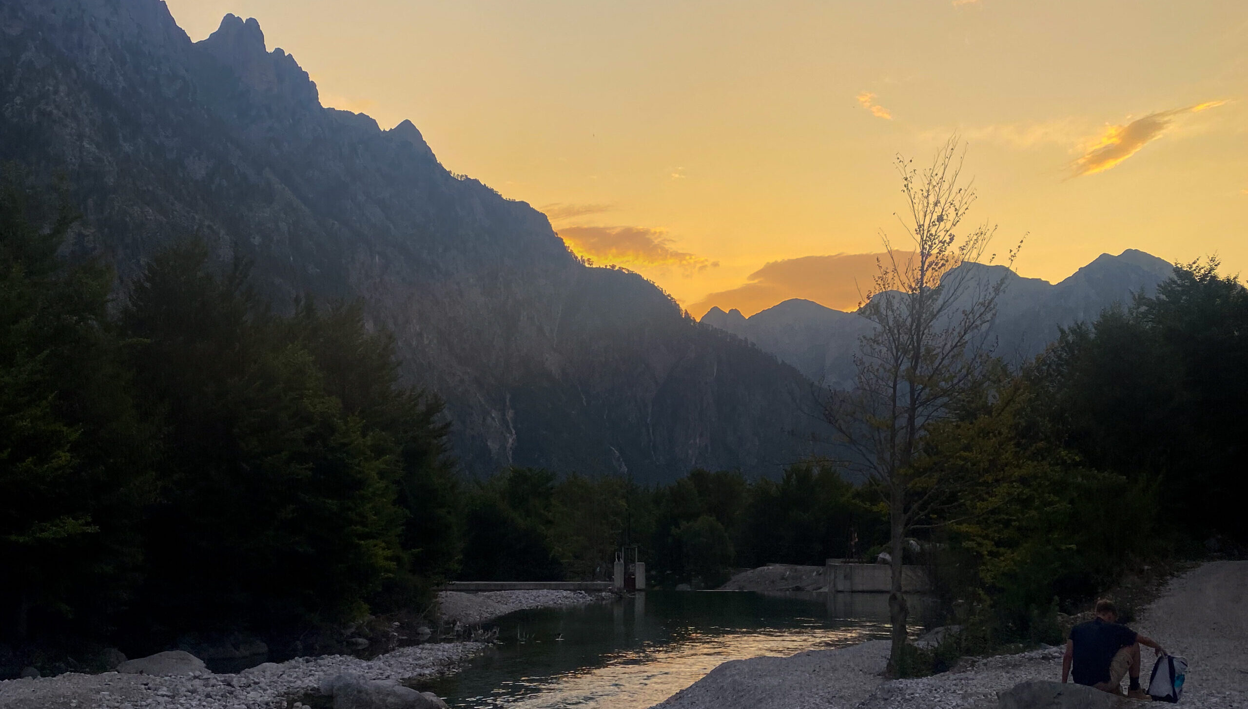 The bright orange sun rising above the distant mountains from a guesthouse in Valbona