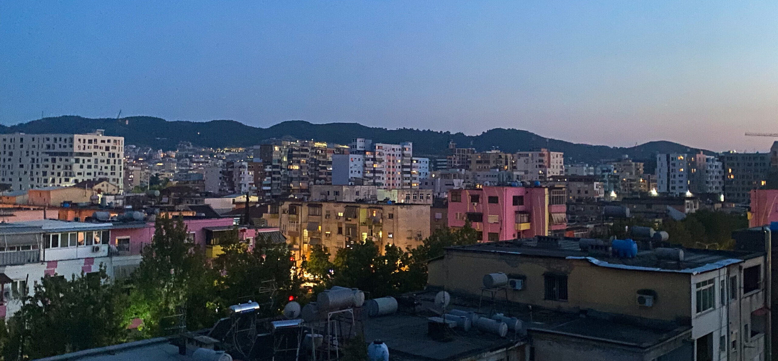 The colourful skyline of Tirana as the sun sets from a budget hostel in central Tirana