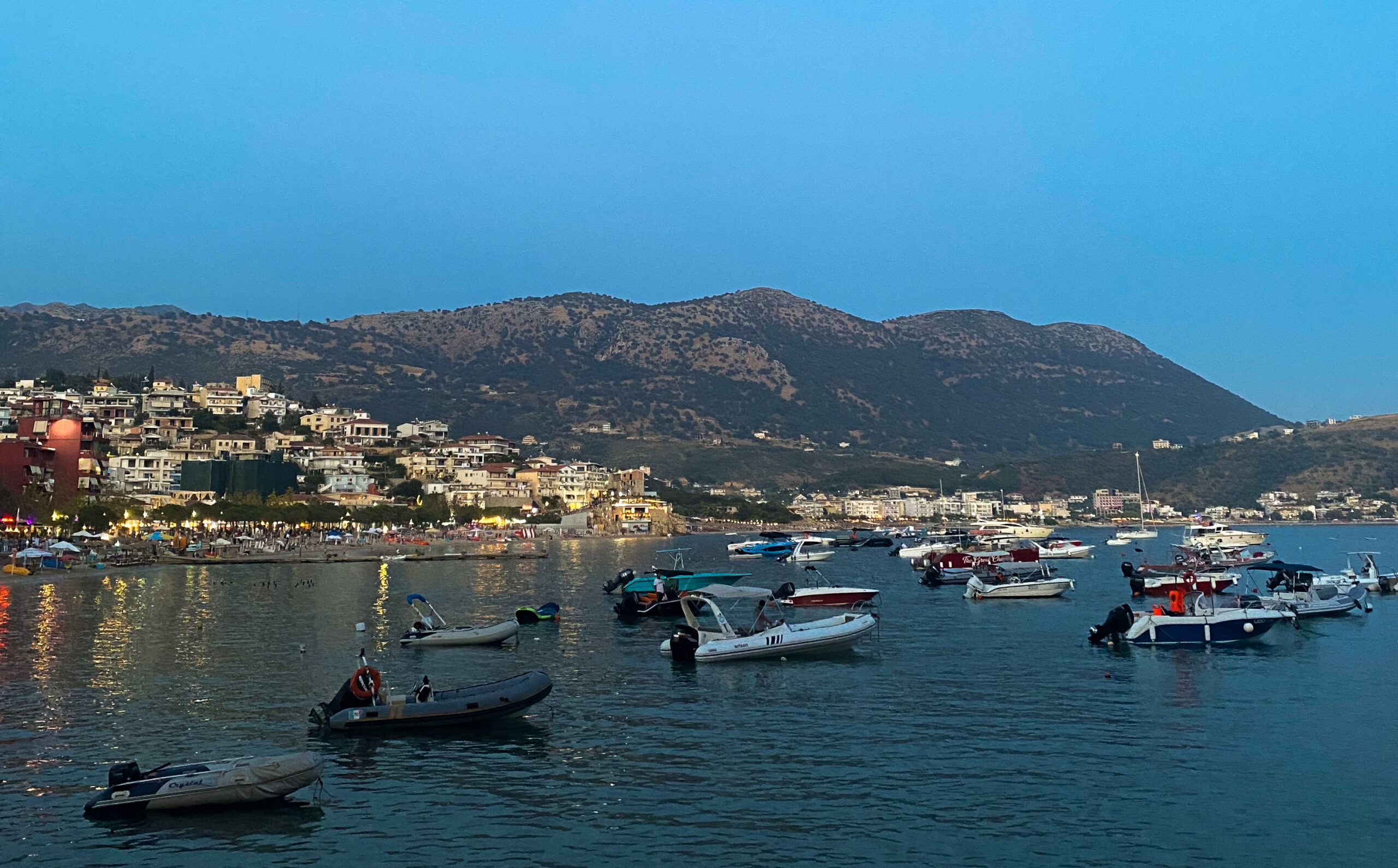 Himarë in the evening with the city lit and mountains in the back