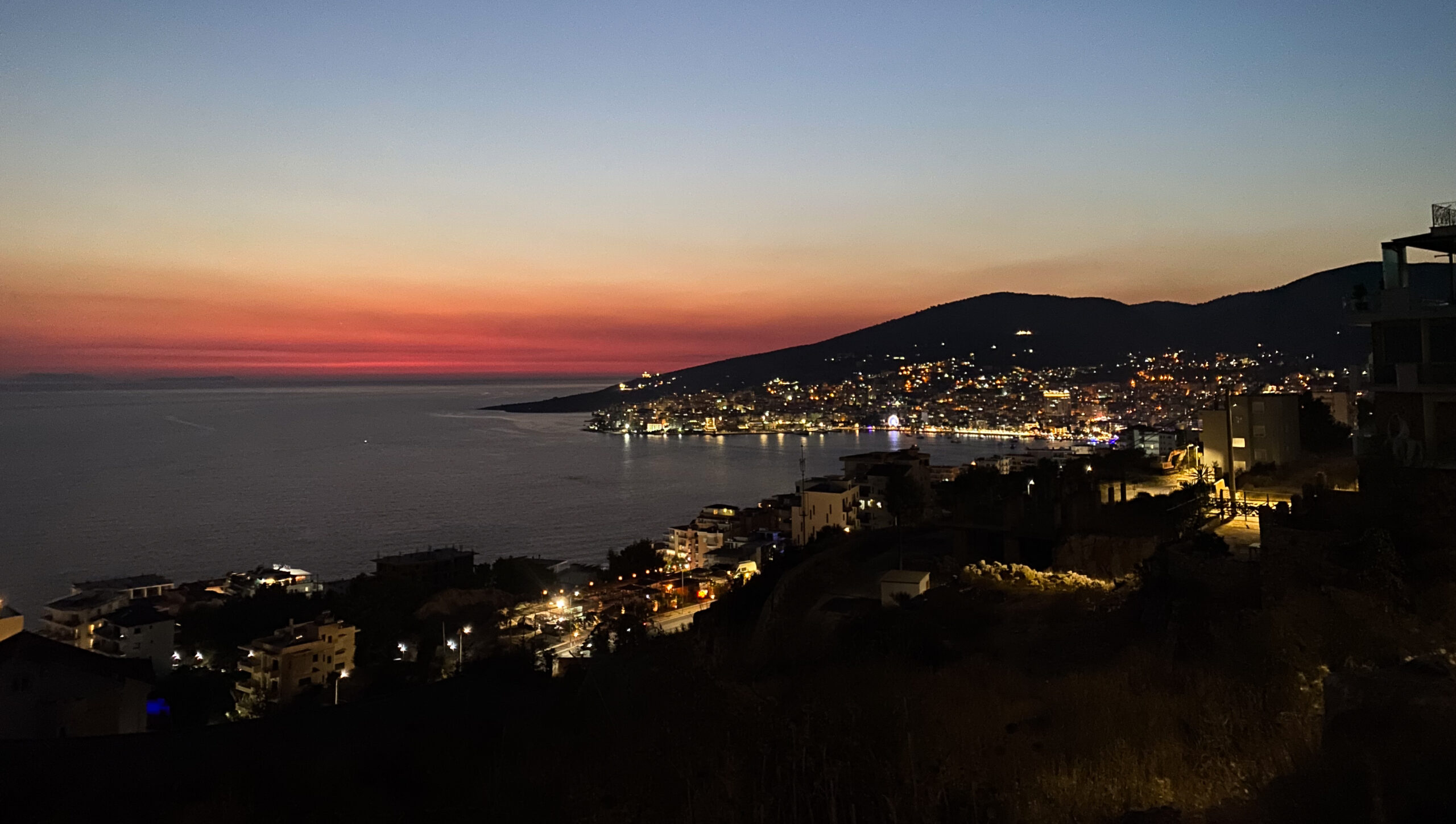 A dreamy sunset over the golden-lit city of Sarandë from the hilltop Lakursi Castle