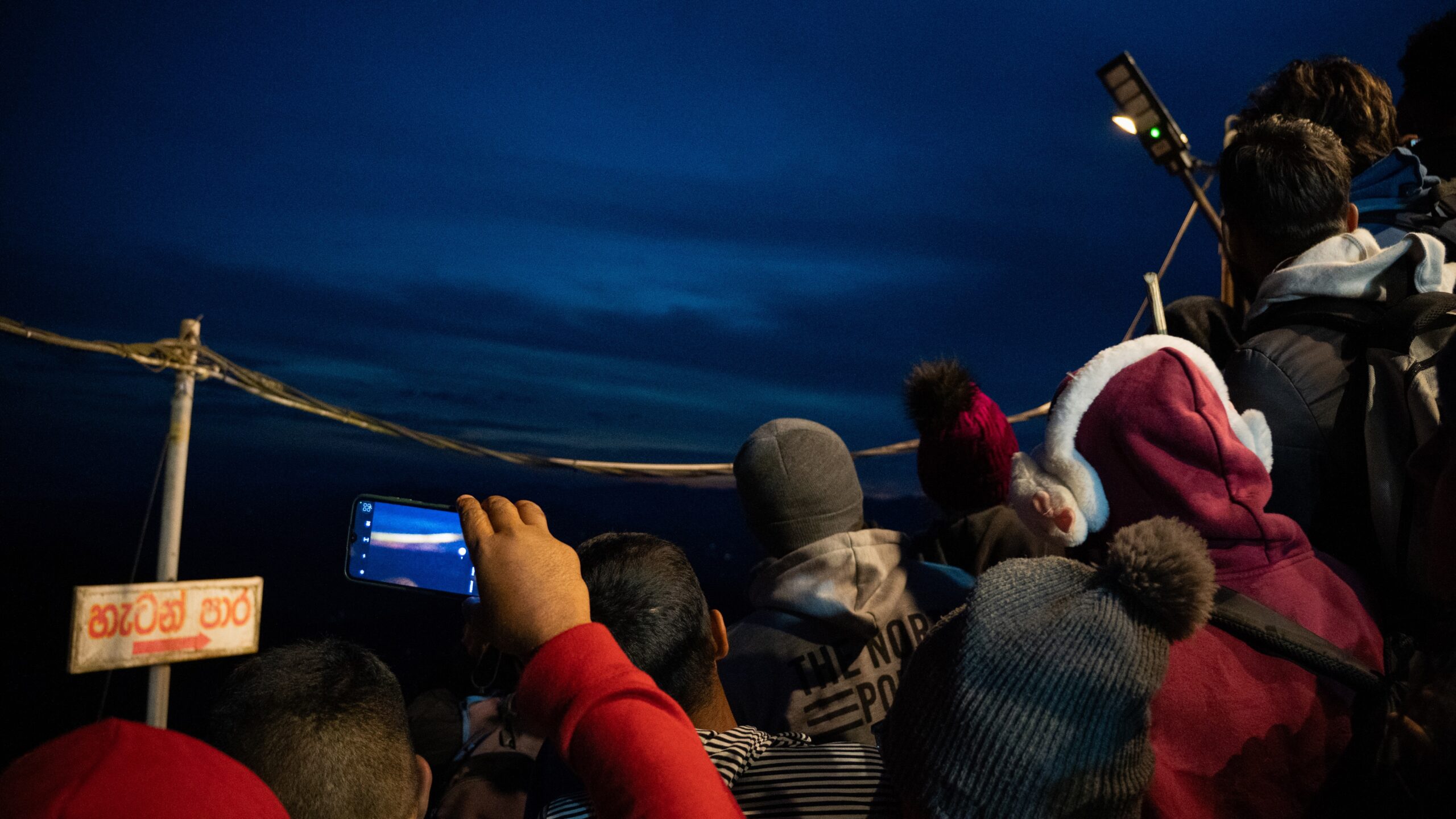 A group of people watching the sun rise over mountains with photos capturing it