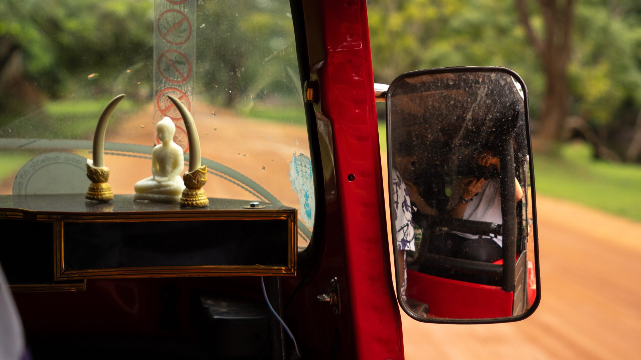 A tuk-tuk driving on the dust road to Sigiriya