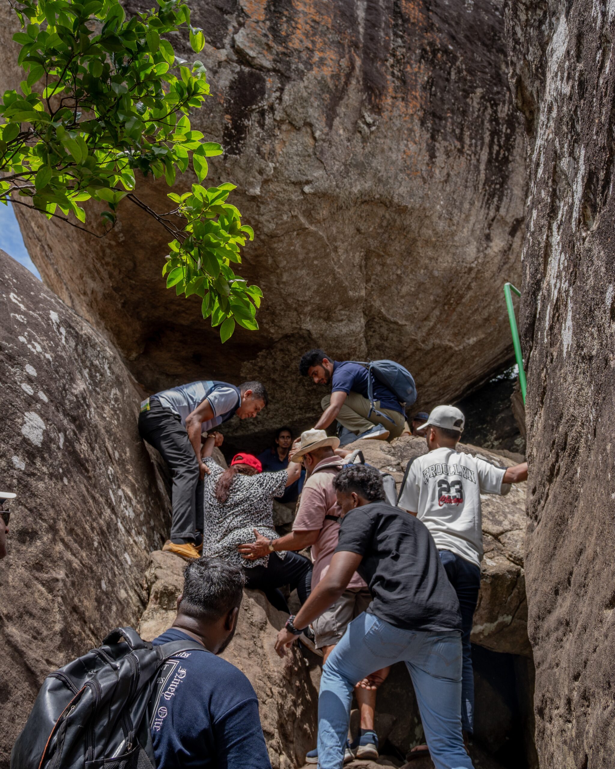 A women being pushed up a boulder to reach Pidurangala Rock, Sigiriya, Sri Lanka