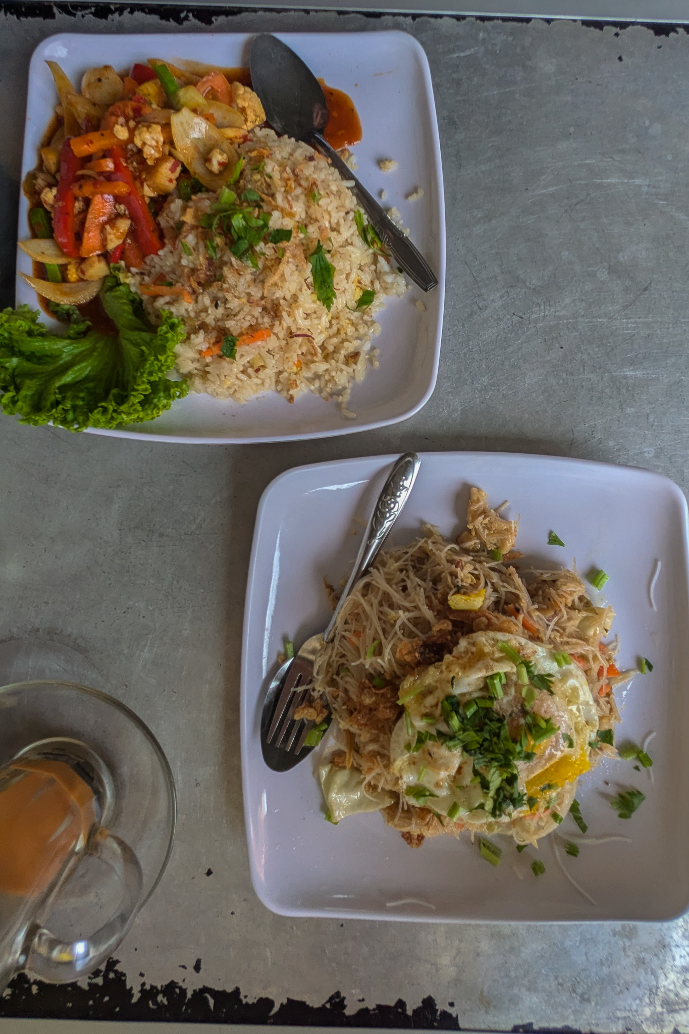 A plate of noodles and a plate of rice at a local spot in Malaysia
