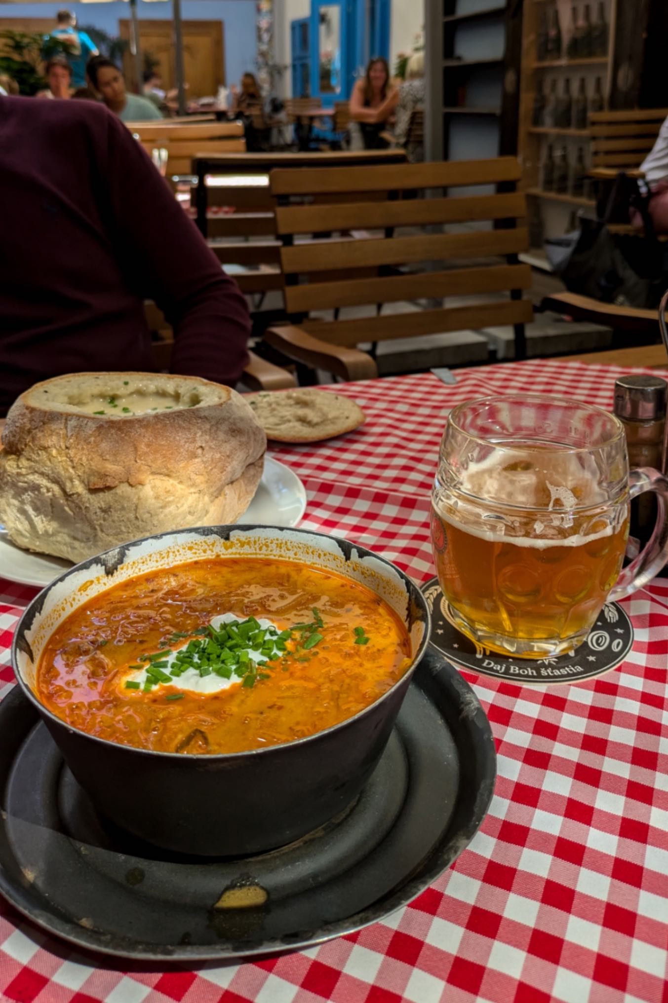 A starter at a traditional Slovak Pub showing a soup and a beer on a red checkered table cloth