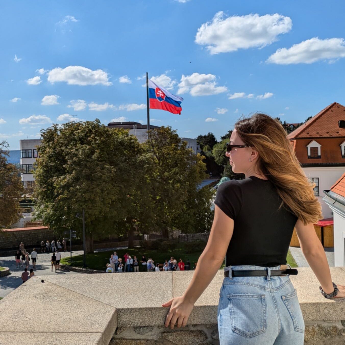 A women stood at a balcony with the Slovakian flag blowing in the background.