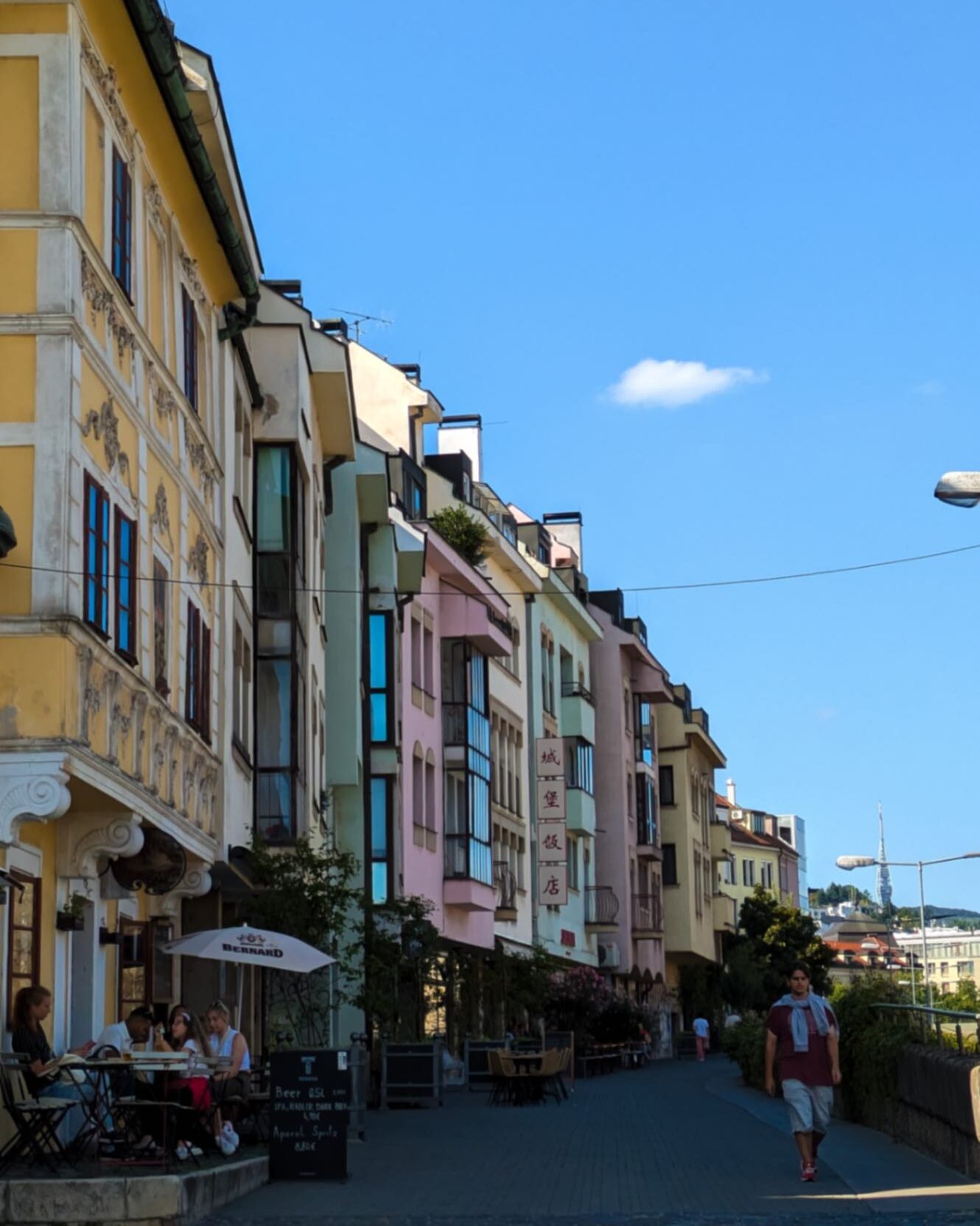 A street colourful in Bratislava with people sat outside cafes.