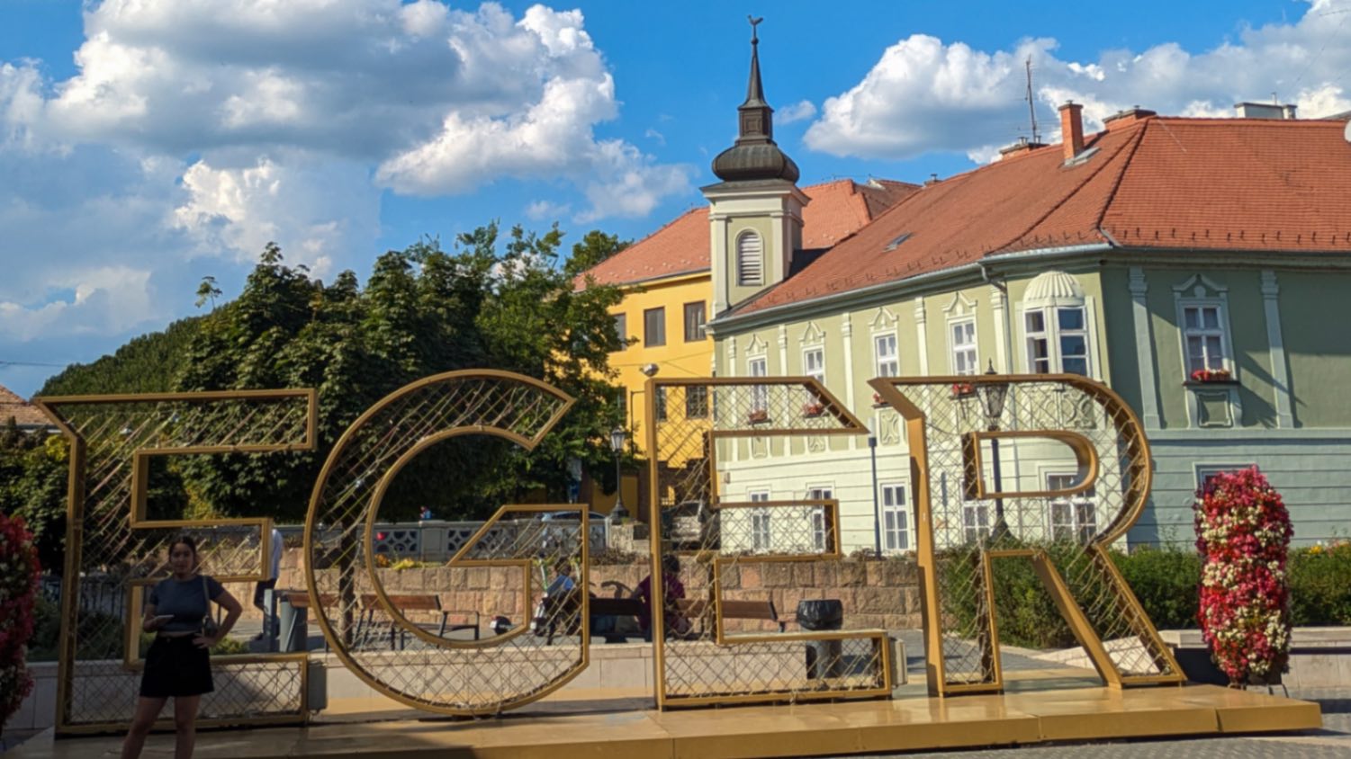 A signage that reads "EGER" outside of gorgeous bright classic Central European buildings