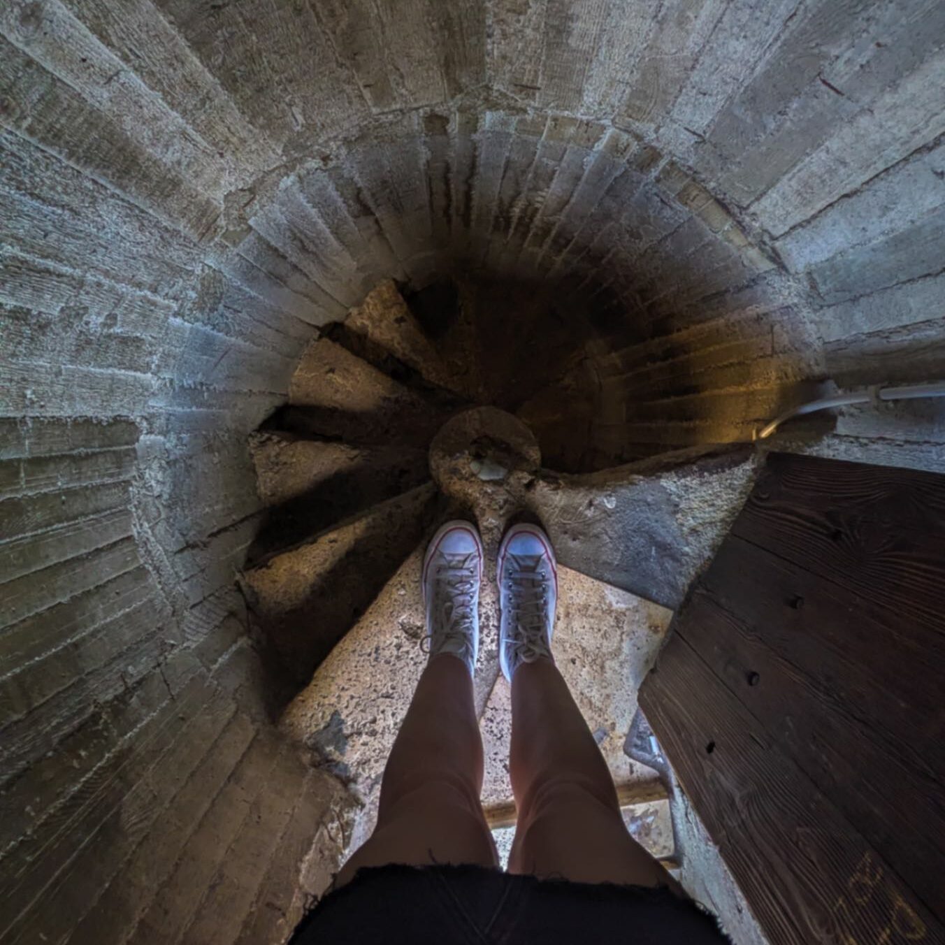 Legs stood over the top of a narrow spiral staircase.