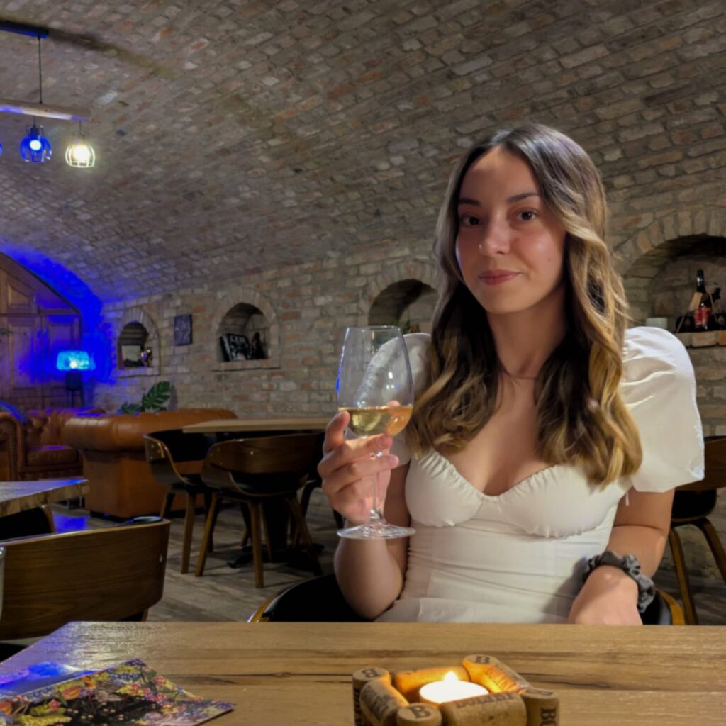 A women holding a glass of white wine in a cave cellar, a unique spot for wine tasting