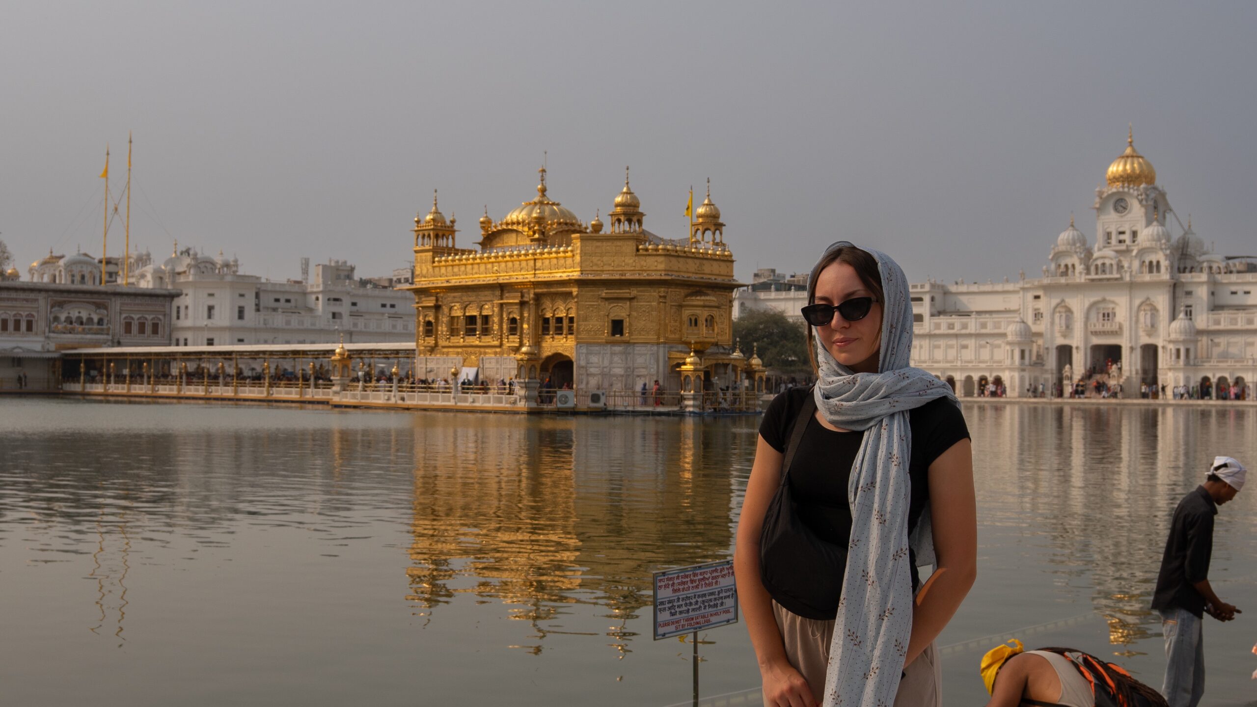 A women stood in front of the Golden Temple in Amritsar - a bright gold Sikh religious site