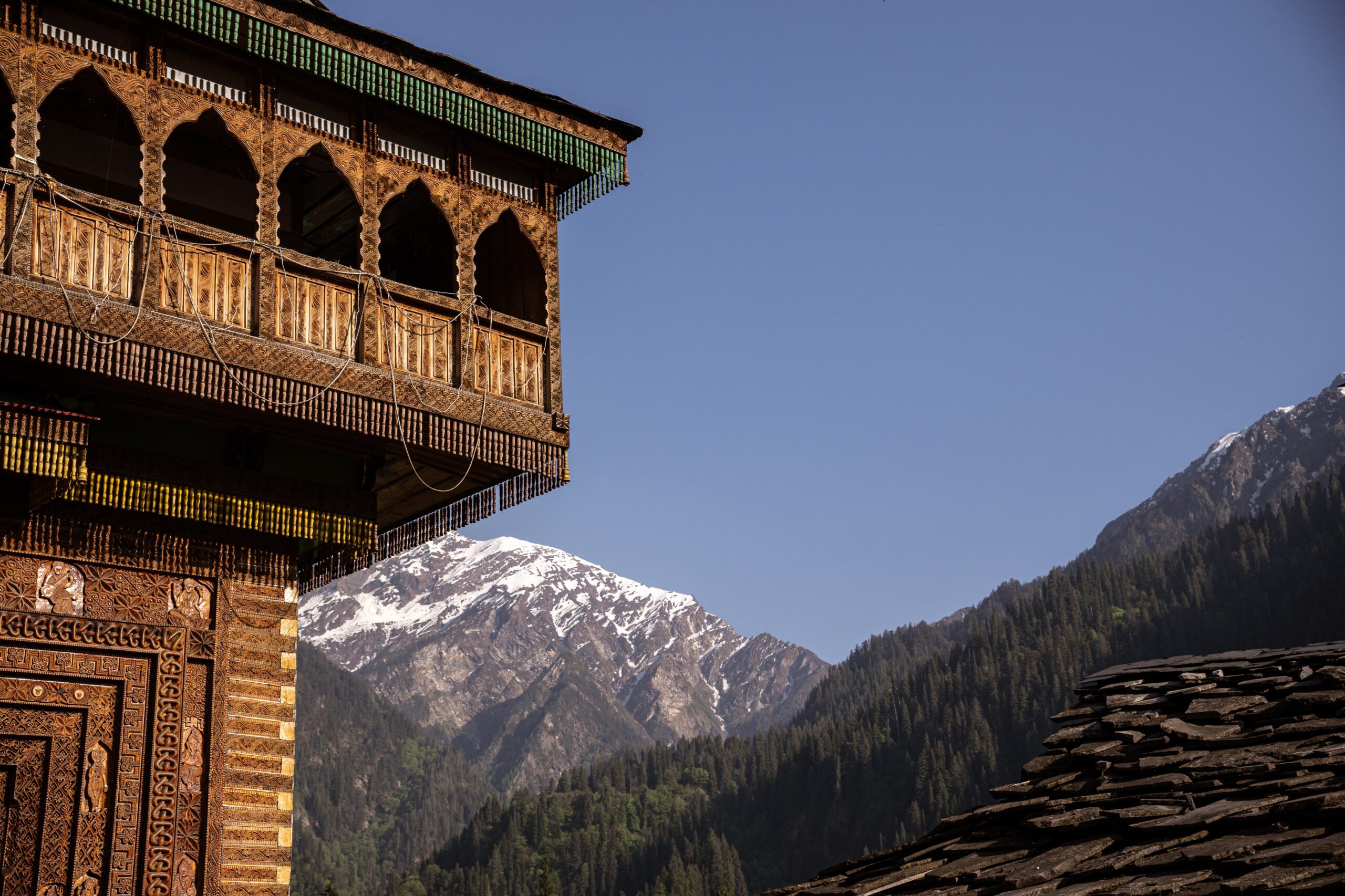 A temple in a small village nearby Kasol in Himachal Pradesh with a mountain in the background.