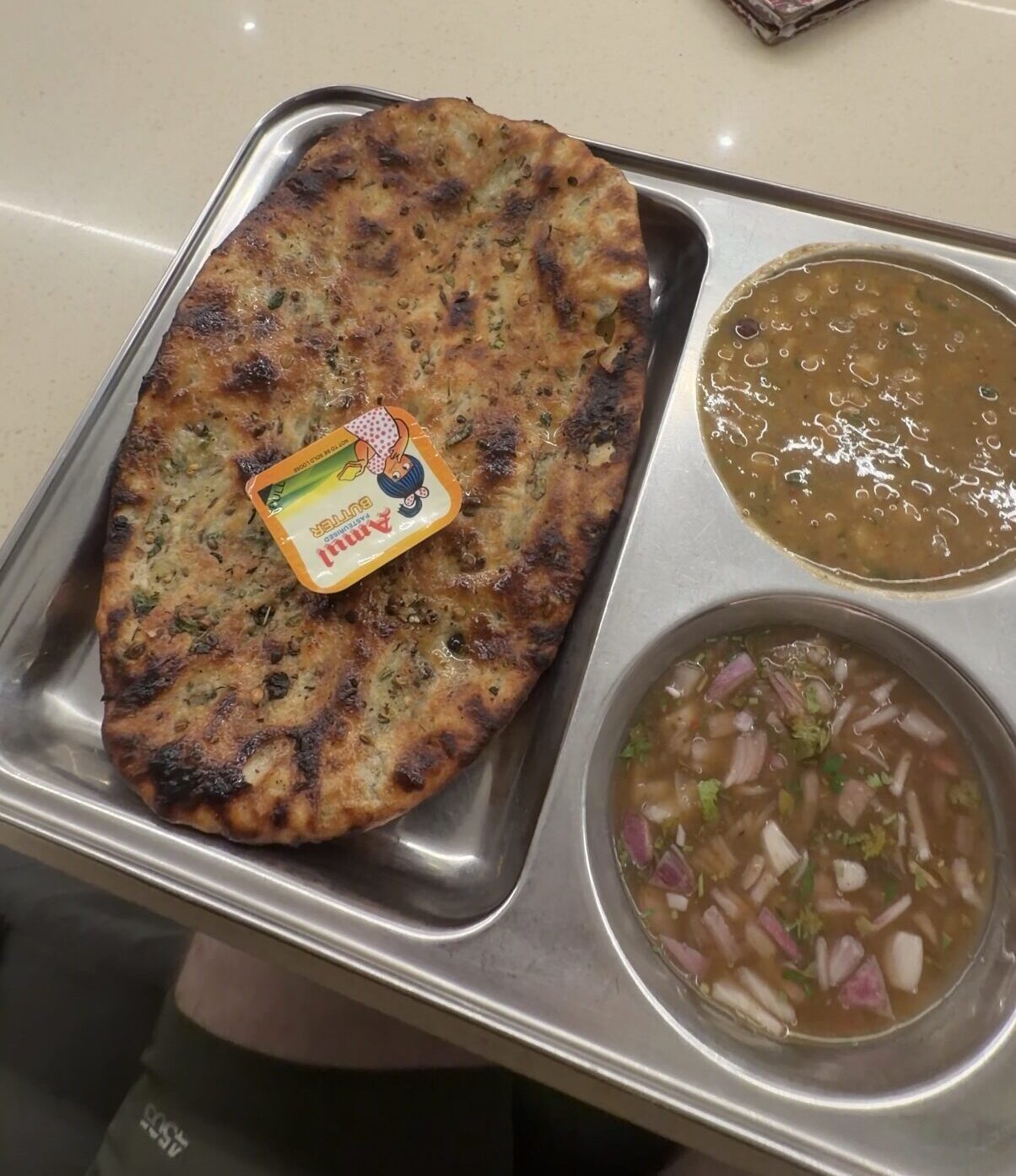 Amritsari Kulcha in a metal tray with a side dish of chickpeas and butter
