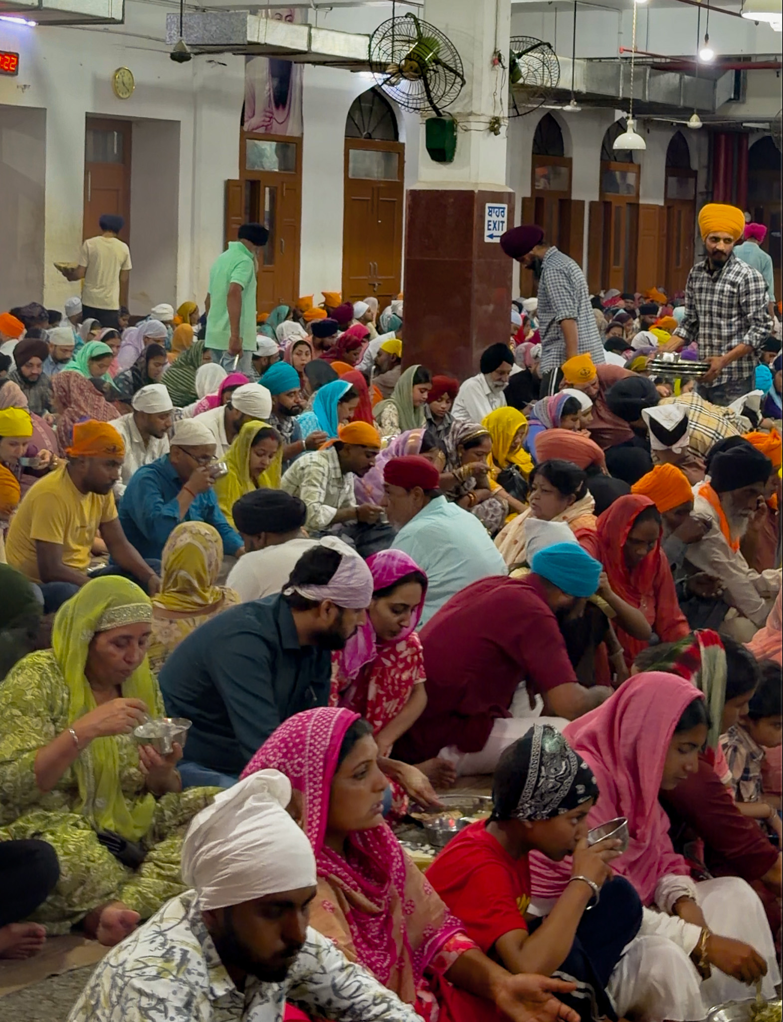Lots of people sat in the community kitchen of the Golden Temple eating foods like dal, roti and rice pudding