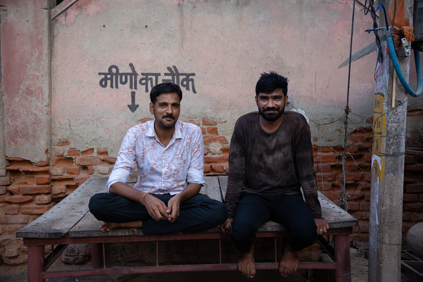 Two Indian men sat on a wooden platform in Bikaner