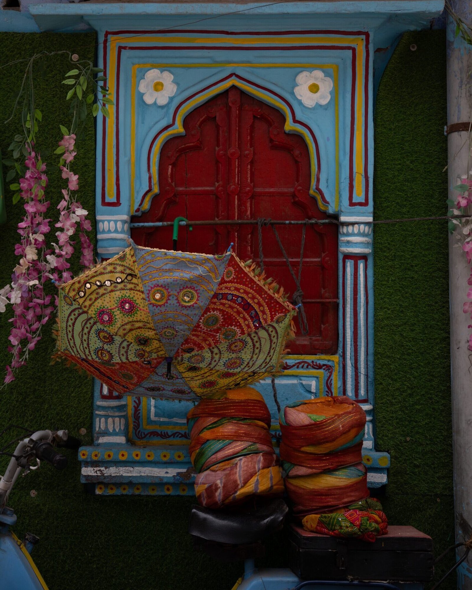 A beautiful blue window with a red inner window with decorations of umbrella and hats