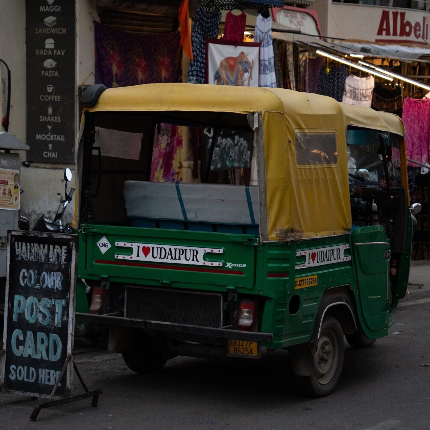 An auto-rickshaw parked at the Old City of Udaipur alongside local vendors selling souvenirs.