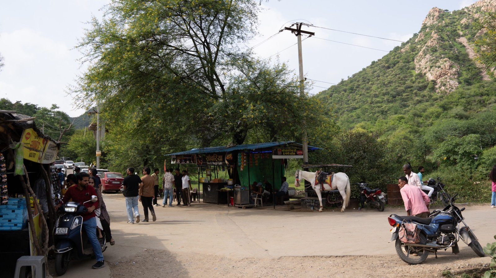 An area with motorbike and food stalls in a nature area of India.