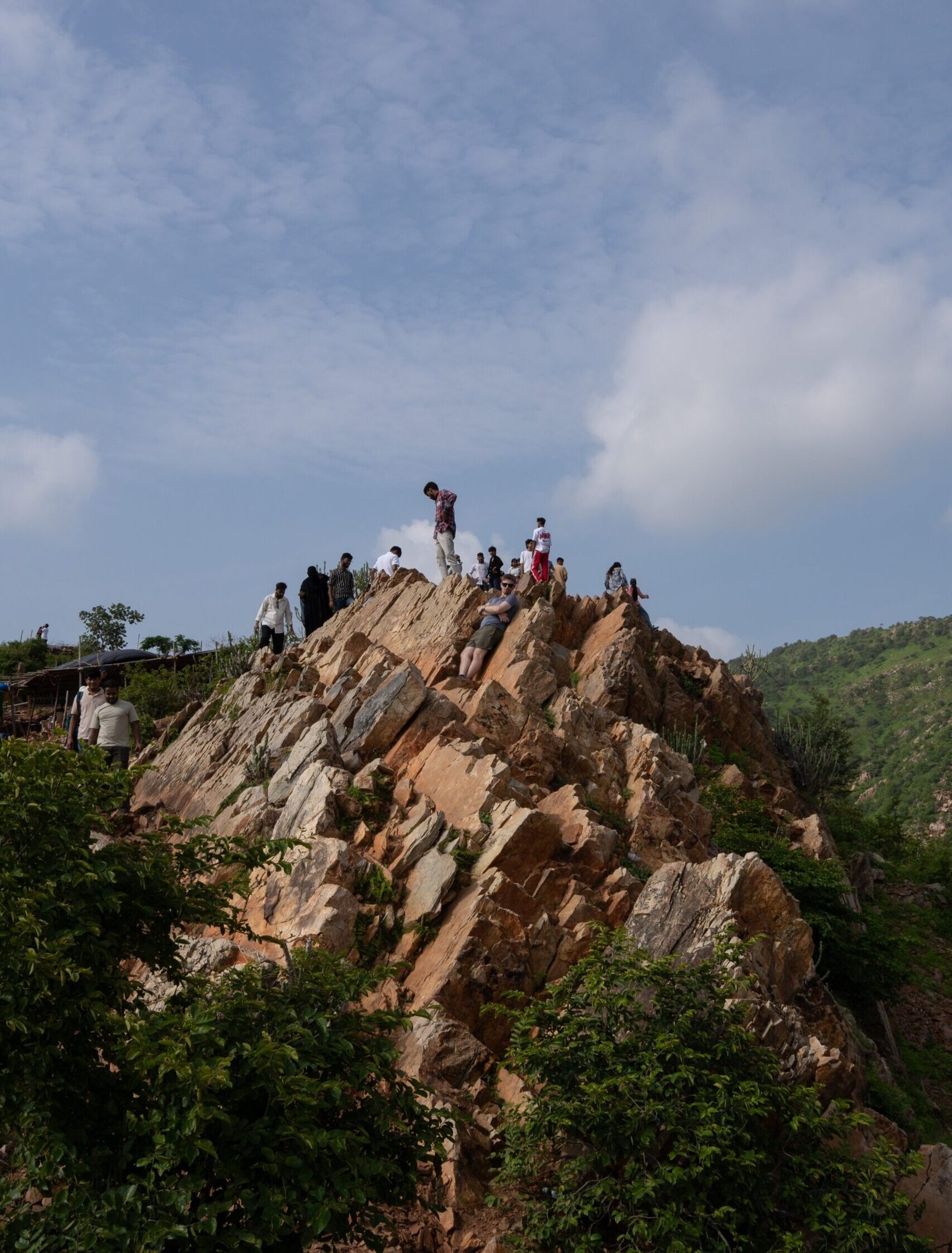 People sat and stood on the edge of a jagged rock face