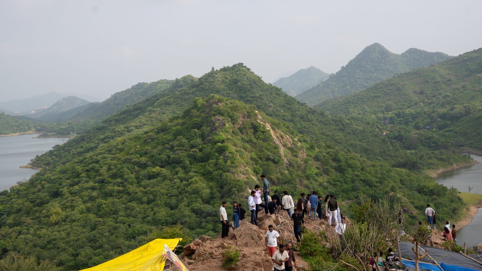 A group of people sat on the cliff edges with hills in the background