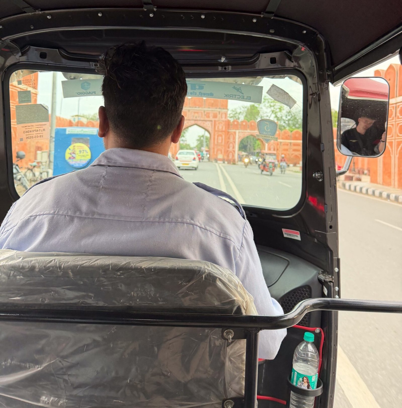 An auto driver in Jaipur with classic architecture on the roads