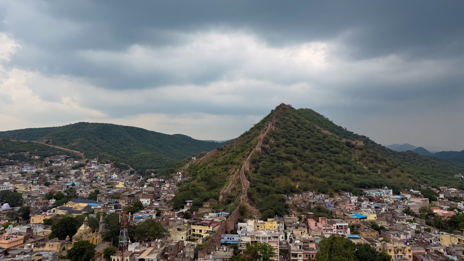 A huge wall going up a hill with a lot of residential below