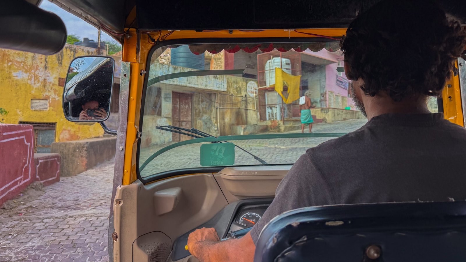 An auto driver driving up a steep narrow road in Jaipur for a view