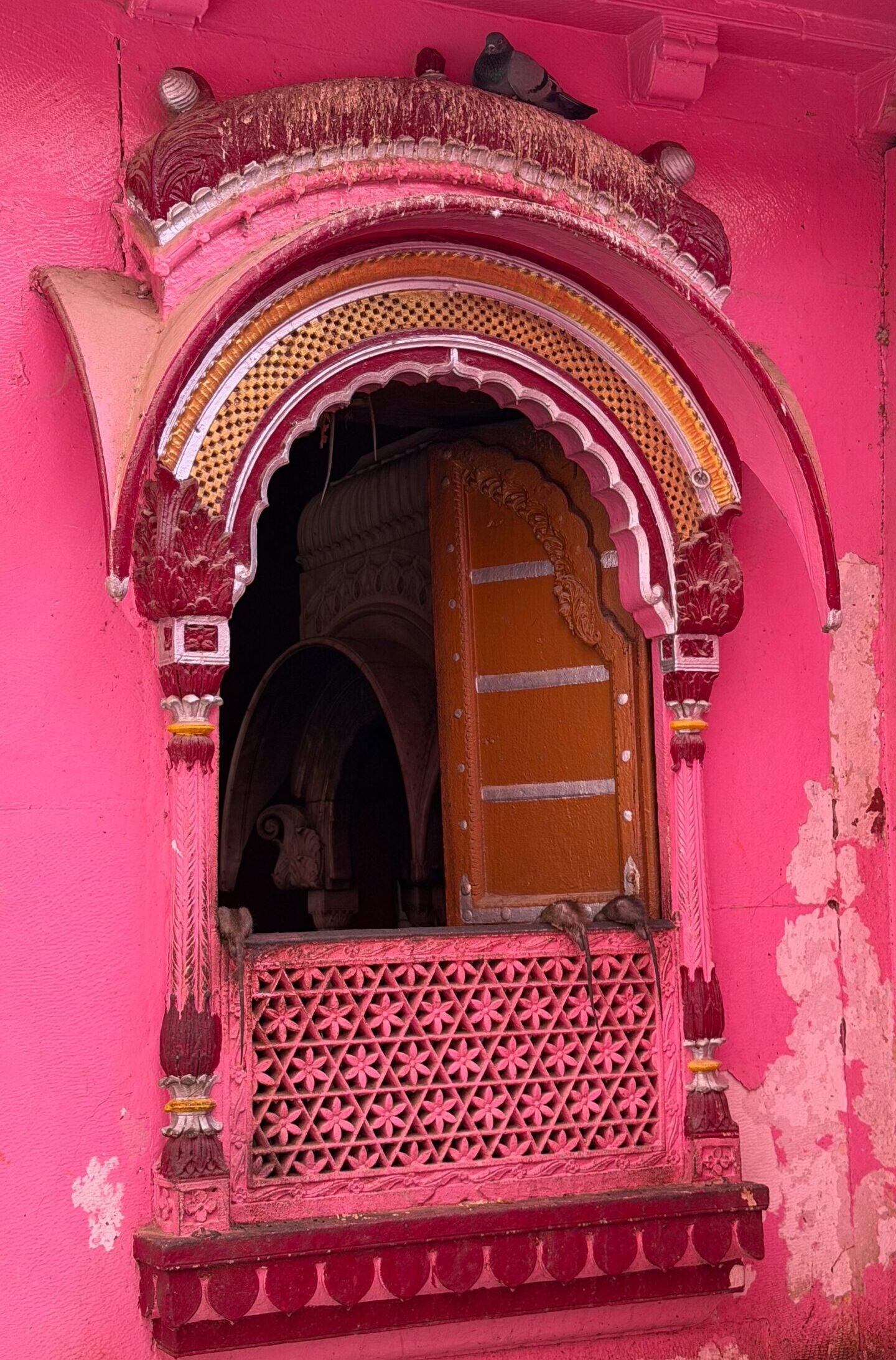 A pink window with traditional Rajasthani architecture
