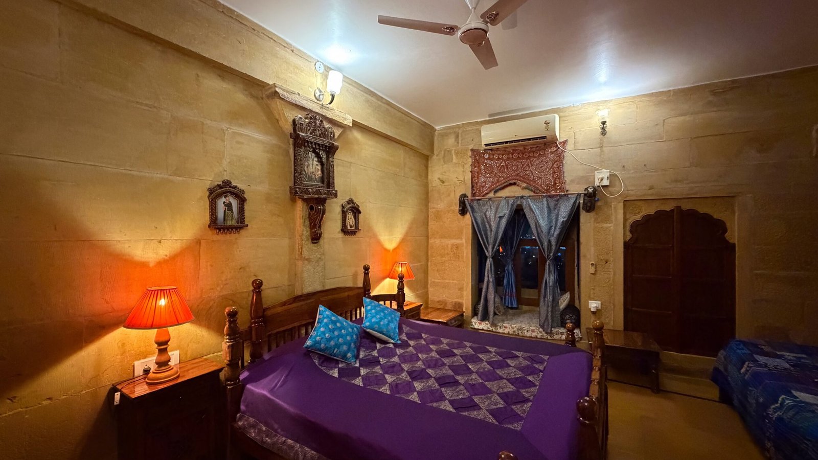 A traditional Rajasthani haveli room with a window seat and purple bedding