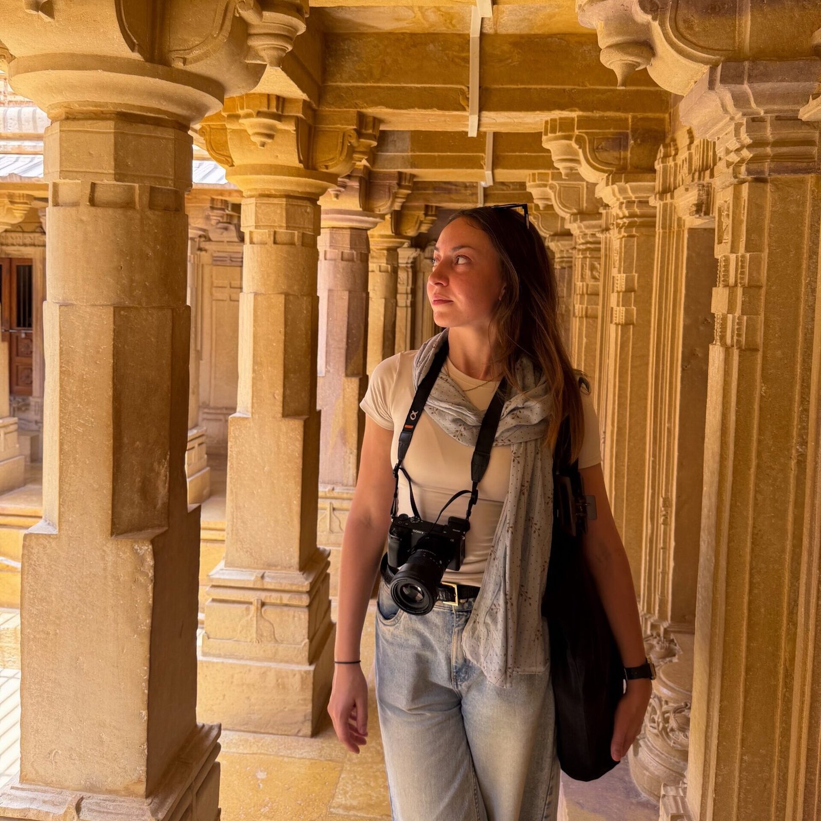 A women walking through a temple, looking up at the pillars