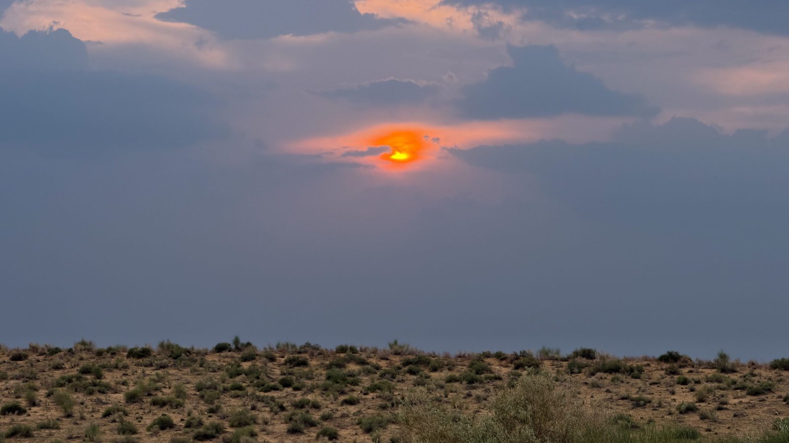 A pink, orange sunset above a desert landscape
