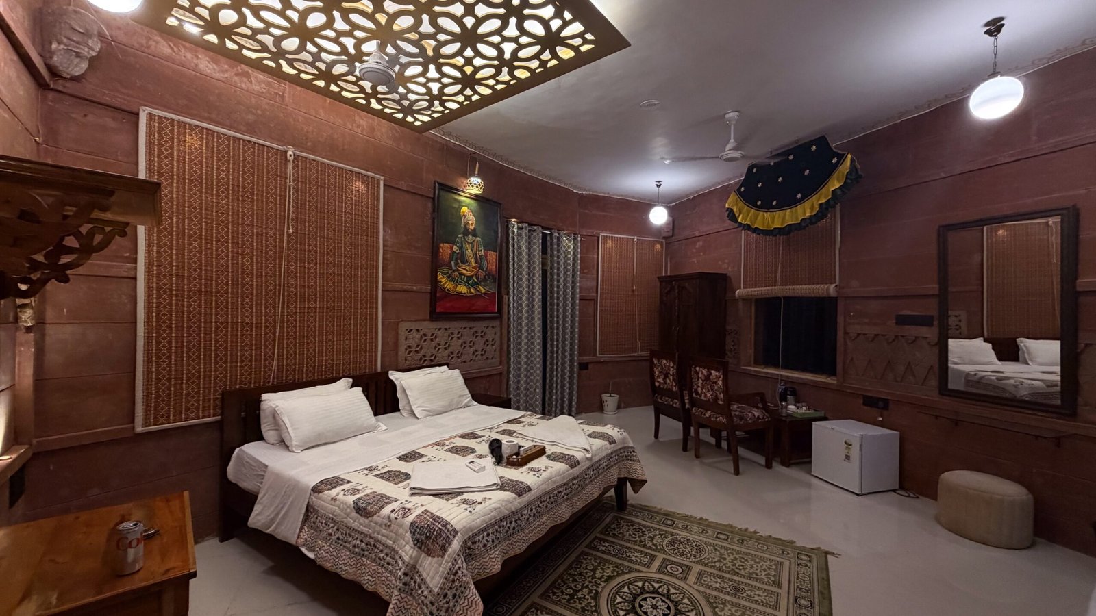 A traditional Rajasthani style room in Jodhpur featuring a bed, a desk, a fridge and wardrobe.
