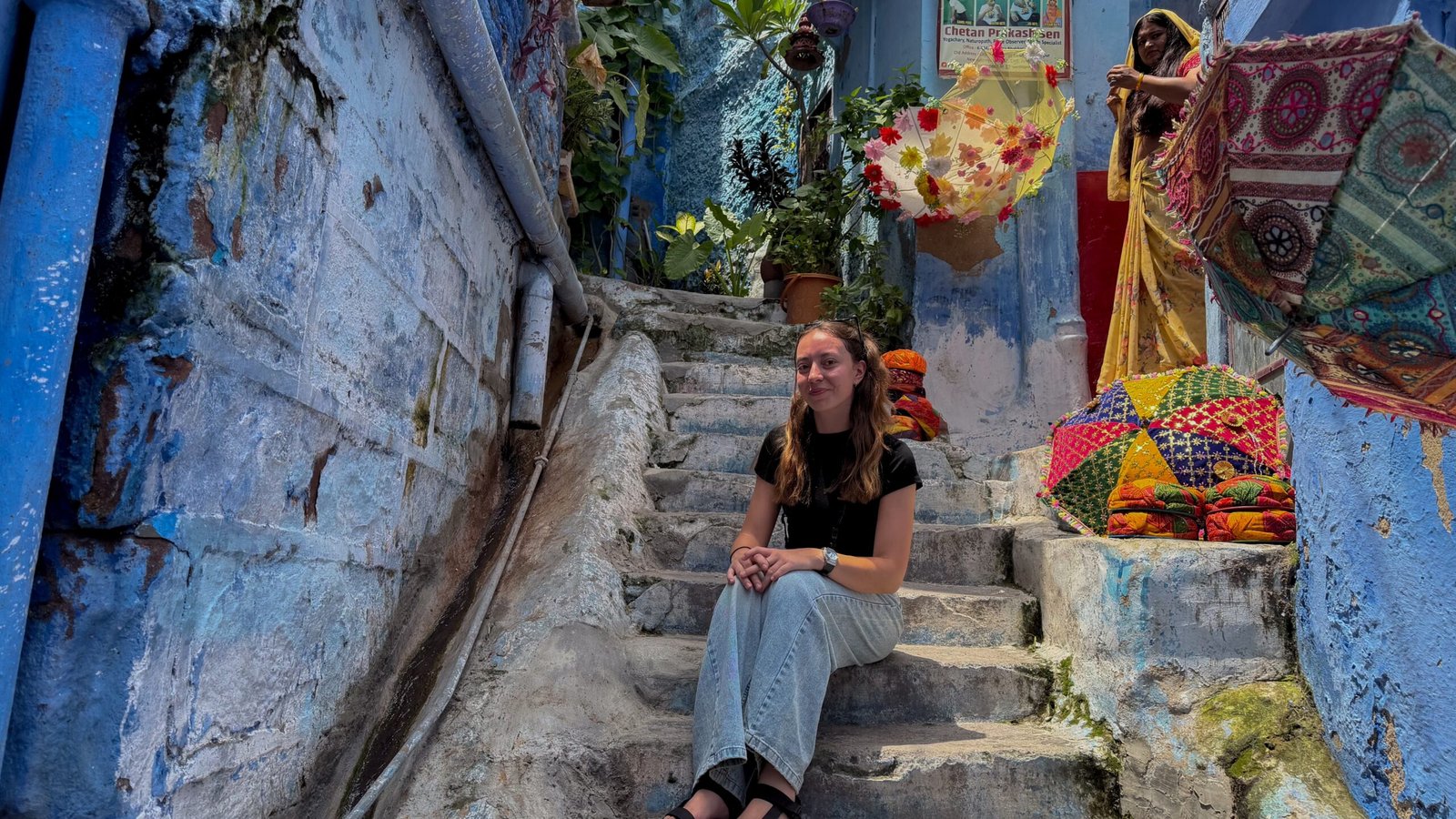 A women sat on a set of stairs in a Blue painted area of Jodhpur