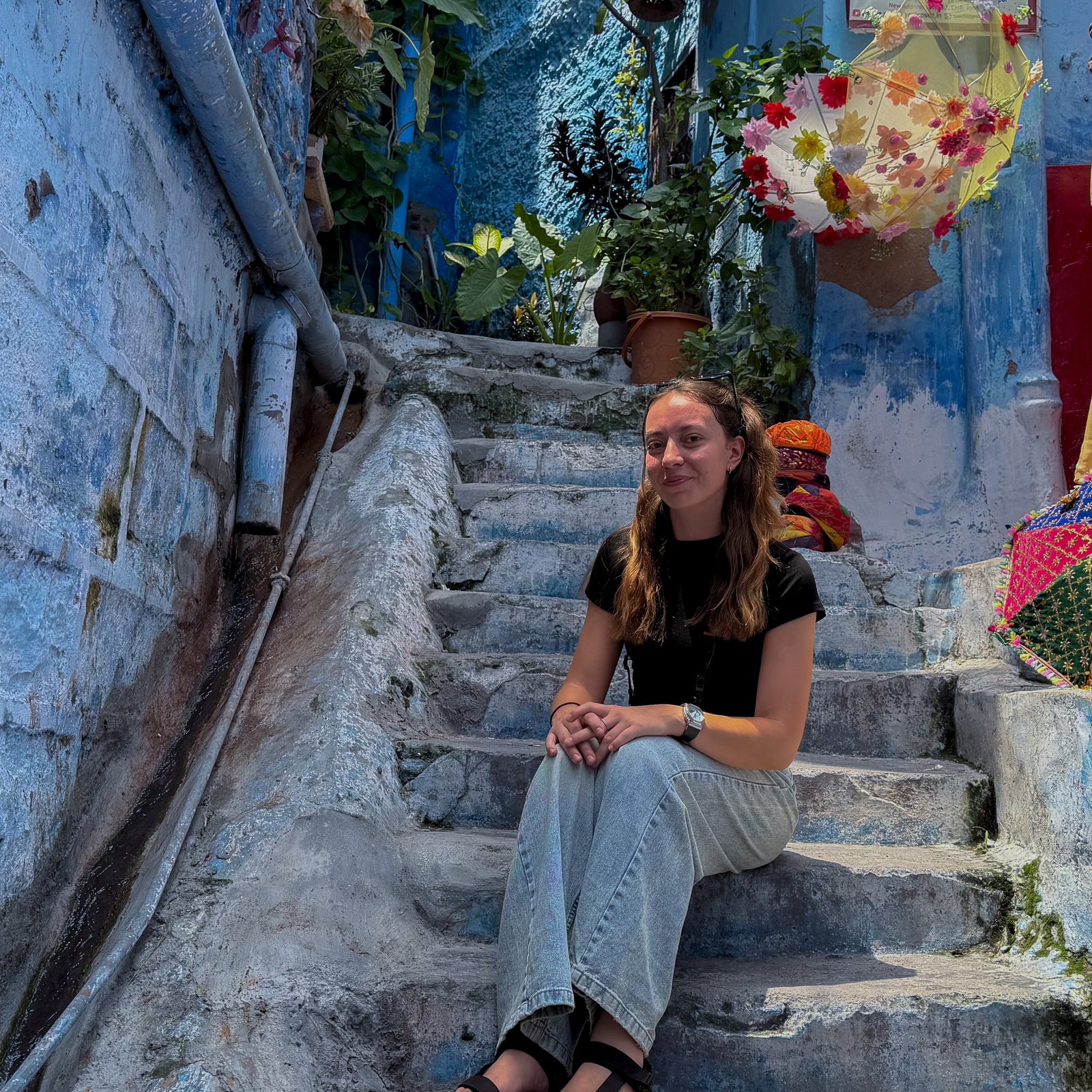 A women sat on a set of stairs in a Blue painted area of Jodhpur - known as the Blue City of India