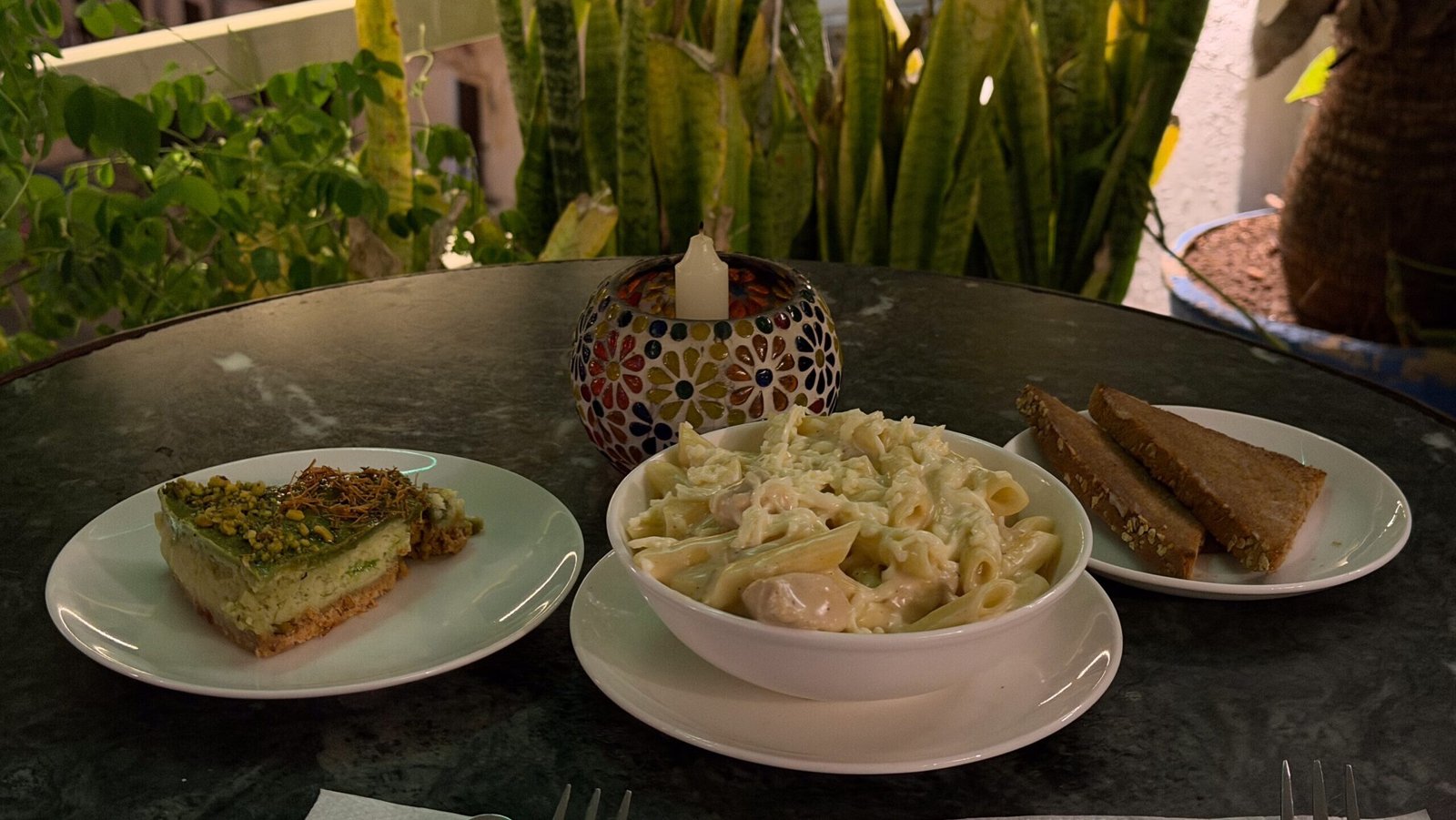 A white sauce pasta with garlic bread and a cheesecake served at a rooftop restaurant