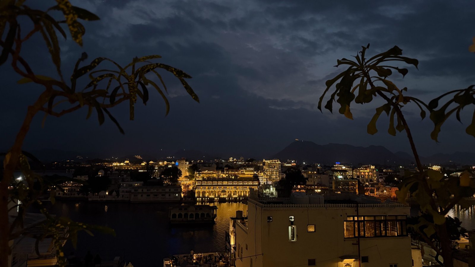 An illuminated city skyline from a rooftop or balcony in Udaipur