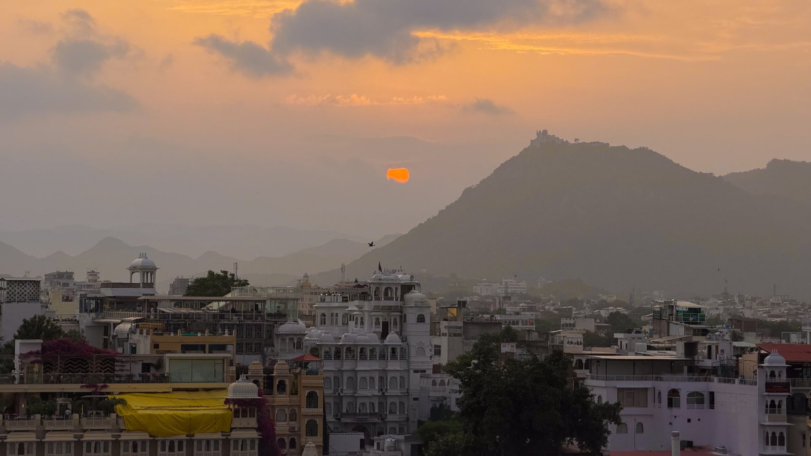 A gorgeous orange sunset sky over the white marble buildings of Udaipur