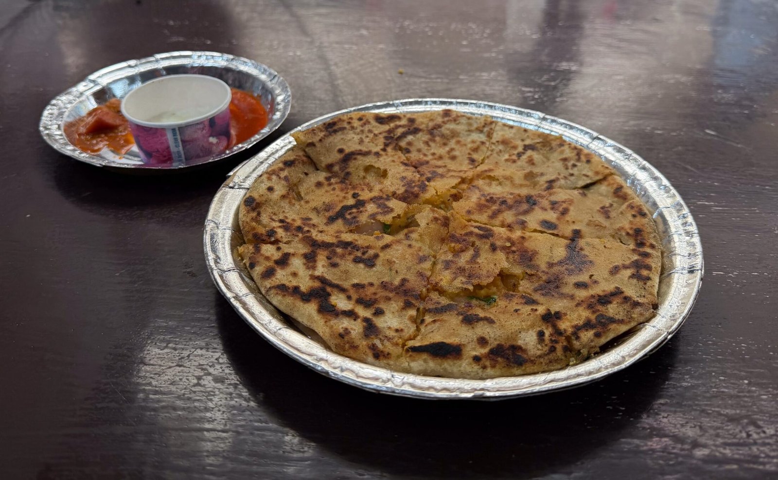 A stuffed paratha with side of pickles, and yogurts