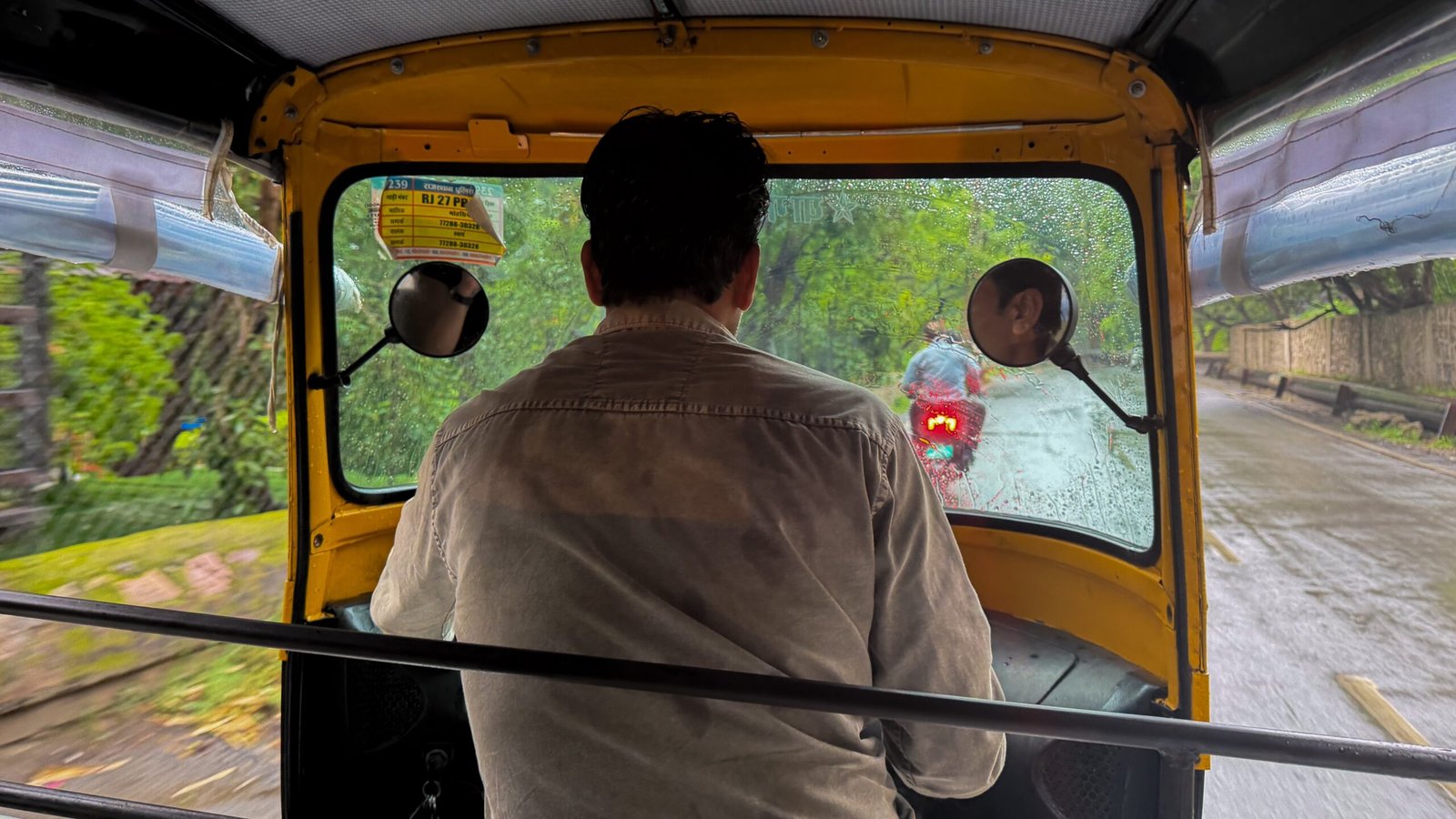 An auto-rickshaw driver driving through the rain in Udaipur
