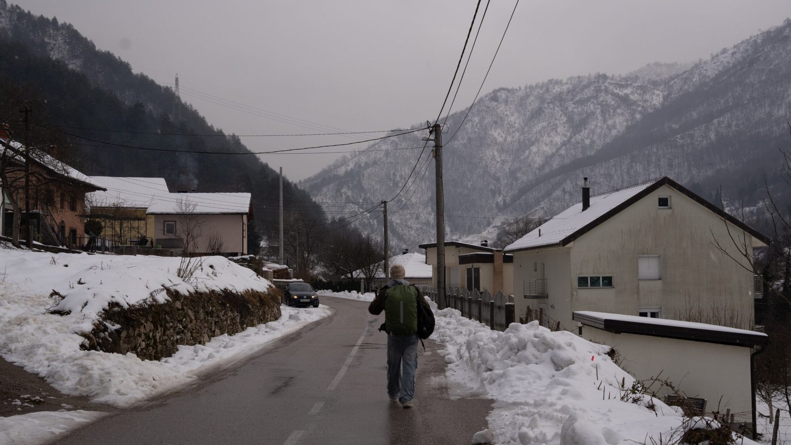 A man walking down roads without cars, covered in snow