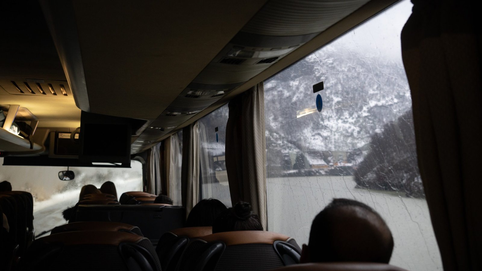 A photo taken from inside a bus with mountains and a river out of the window in Bosnia