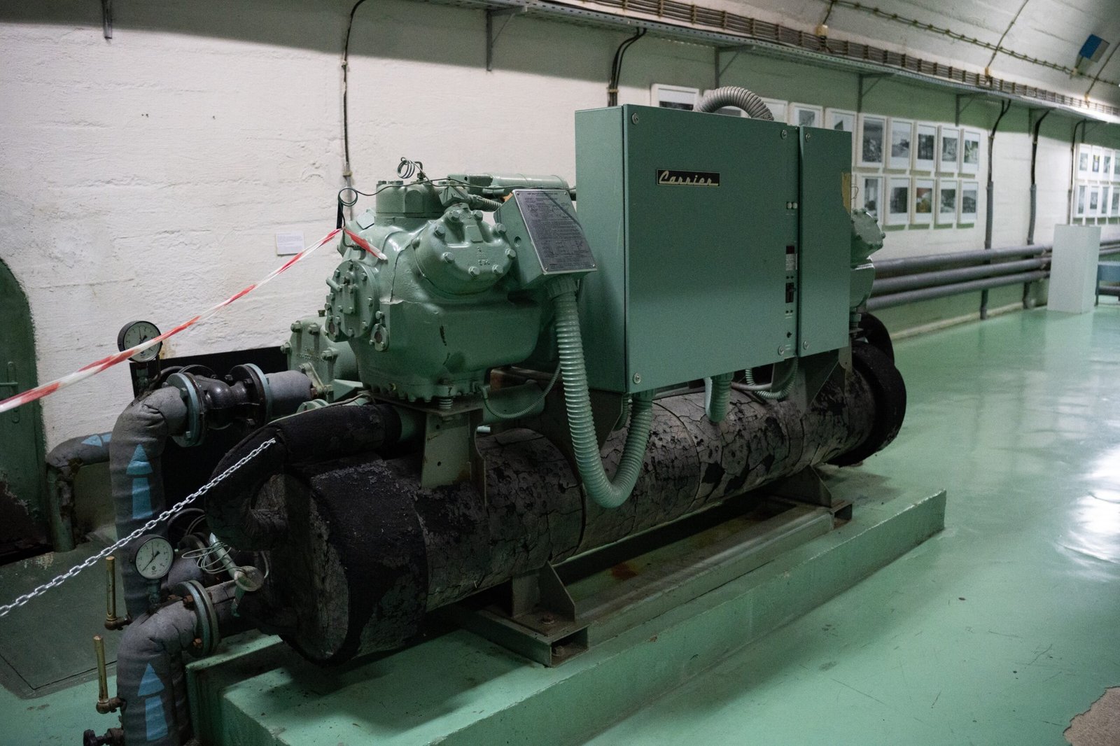 A large generator inside a bunker with green floors and white walls
