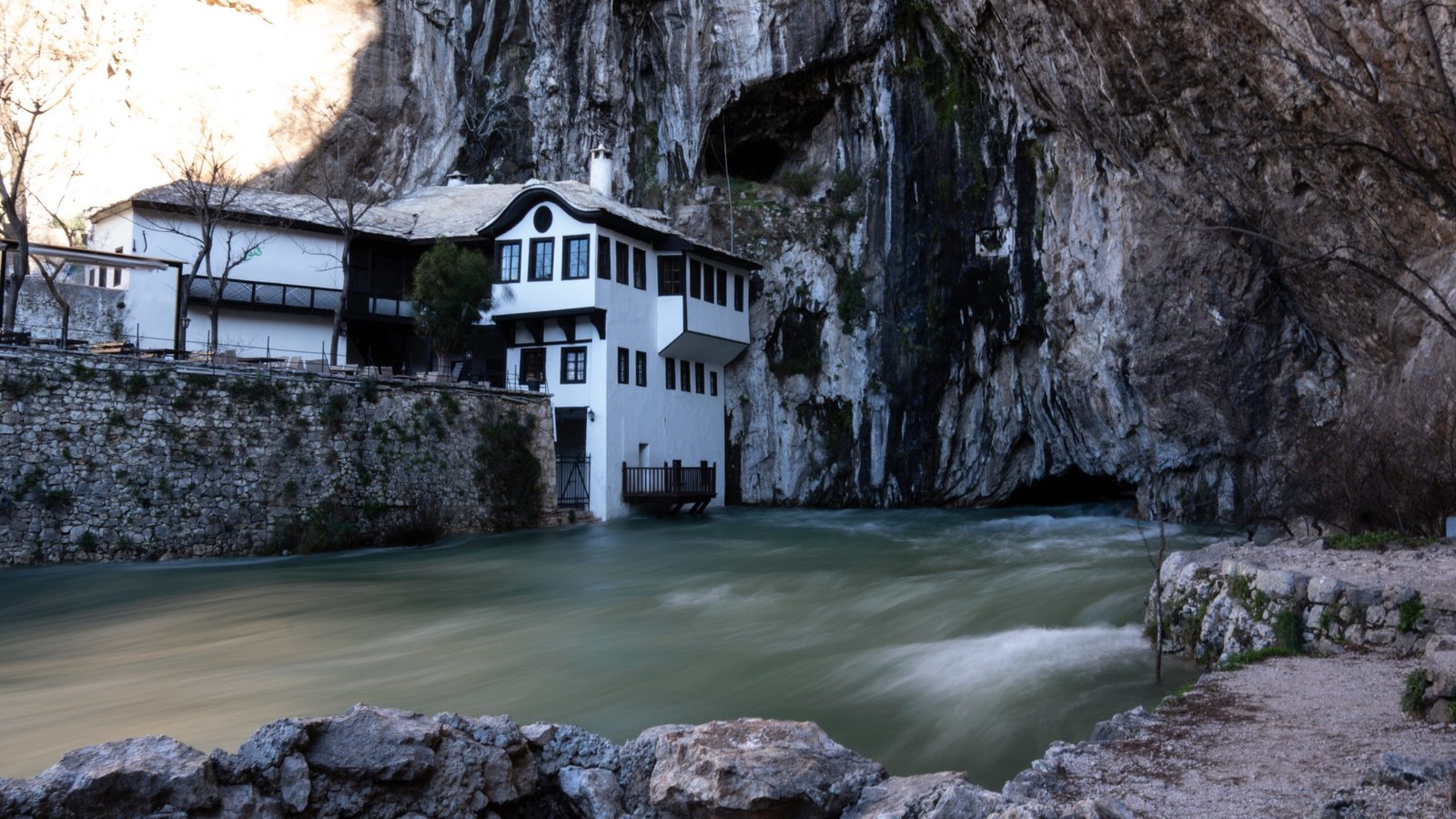 Flowing water coming from a cave with a monastery in Bosnia