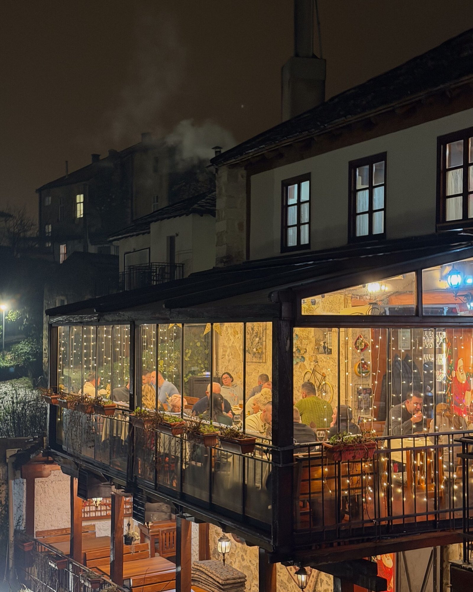 A glass shelter with a restaurant inside over a river in Mostar