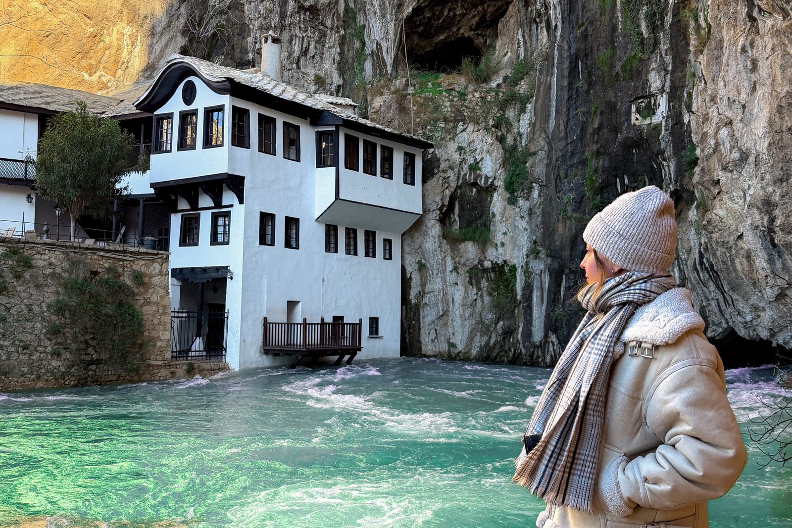 A women stood next to a monastery and green waters on a day trip from Mostar in Herzegovina