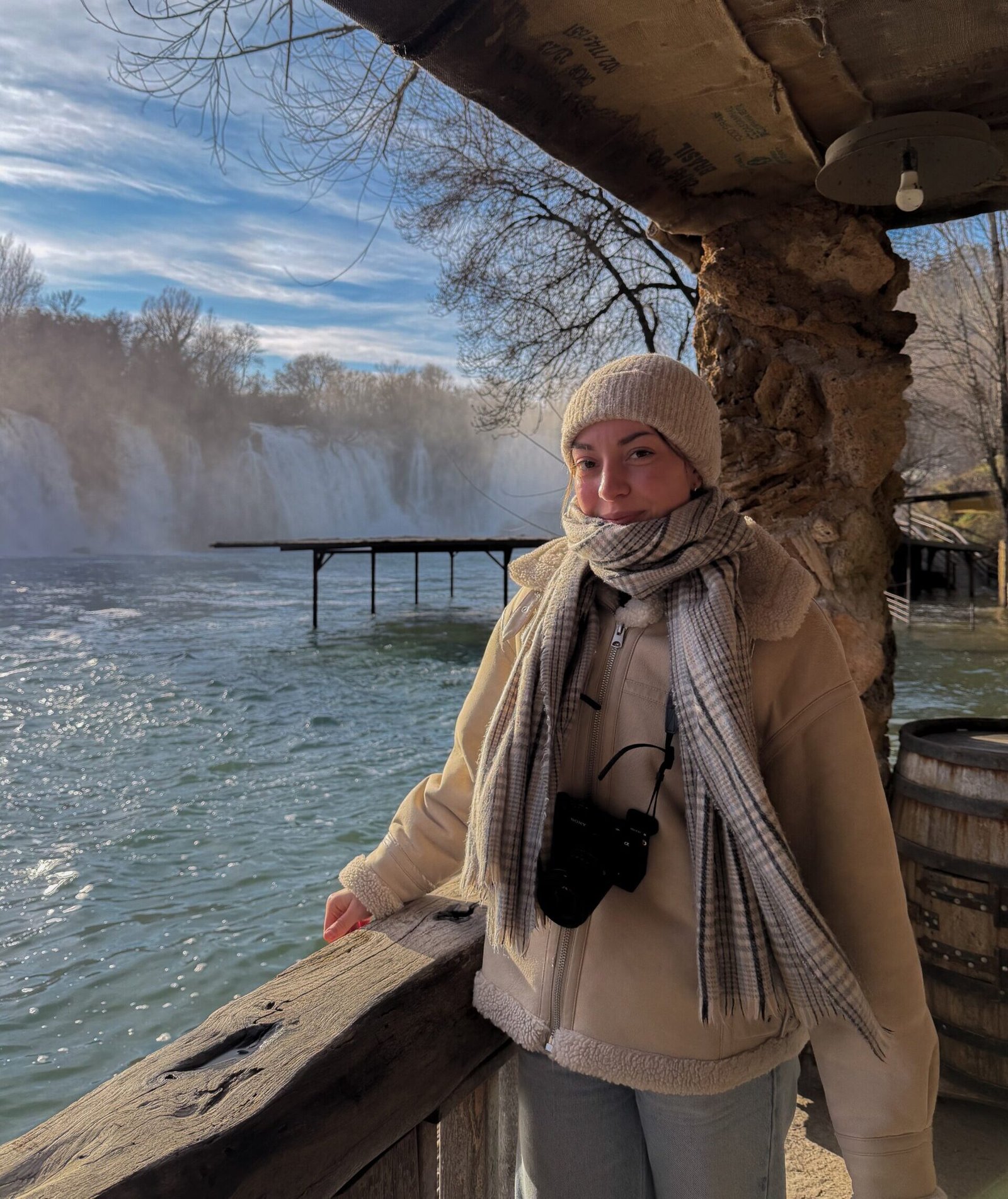 A women stood at a lookout for a waterfall, wrapped up in layers